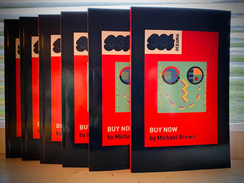 A stack of books with the album 'Buy Now' by Eyeliner on their cover.