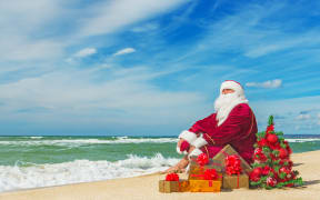 Santa Claus at sea beach with many gifts and decorated christmas tree - happy new year concept