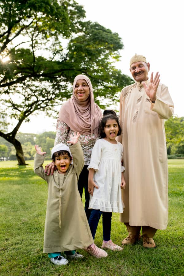 Two Muslim grandparents with two small children in a park.