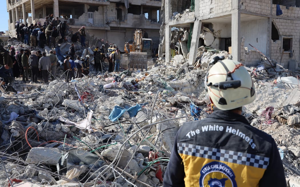 Rescue workers look for survivors amid the rubble of a building in the rebel-held Syrian town of Jindayris on 9 February 2023, three days after a deadly earthquake that hit Turkey and Syria.