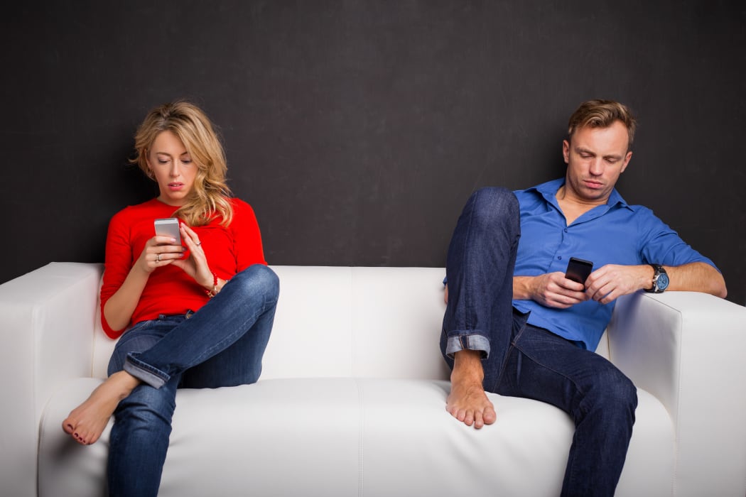 couple on couch each on phones