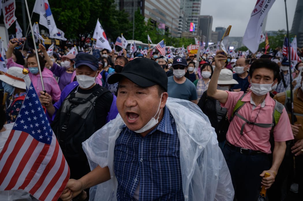 Members of pro-US conservative right-wing and religious christian groups wave flags and shout slogans during the 15 August anti-government rally