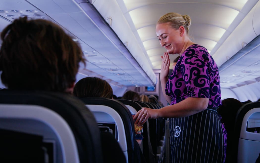 A crew member signs "thank you" on board flight NZ421 from Auckland to Wellington.