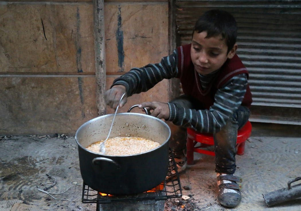 A child cooks on the street in Aleppo.