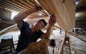 A craftsman measures a dragon boat at Fangzhongxiong dragon boat factory in Fangzhuang Village of Nantong Township in Minhou County of Fuzhou, southeast China's Fujian Province.