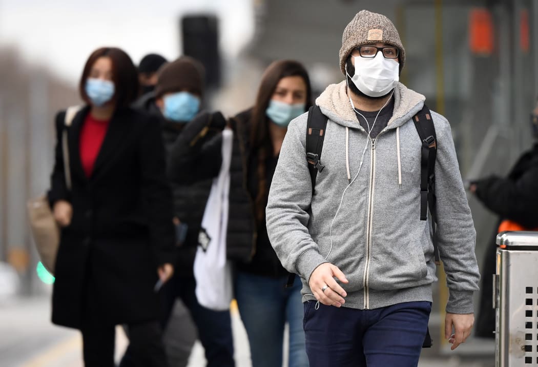 Commuters walk past Melbourne's Flinders Street Station on July 23, 2020 on the first day of the mandatory wearing of face masks in public areas as the city experiences an outbreak of the COVID-19 coronavirus.