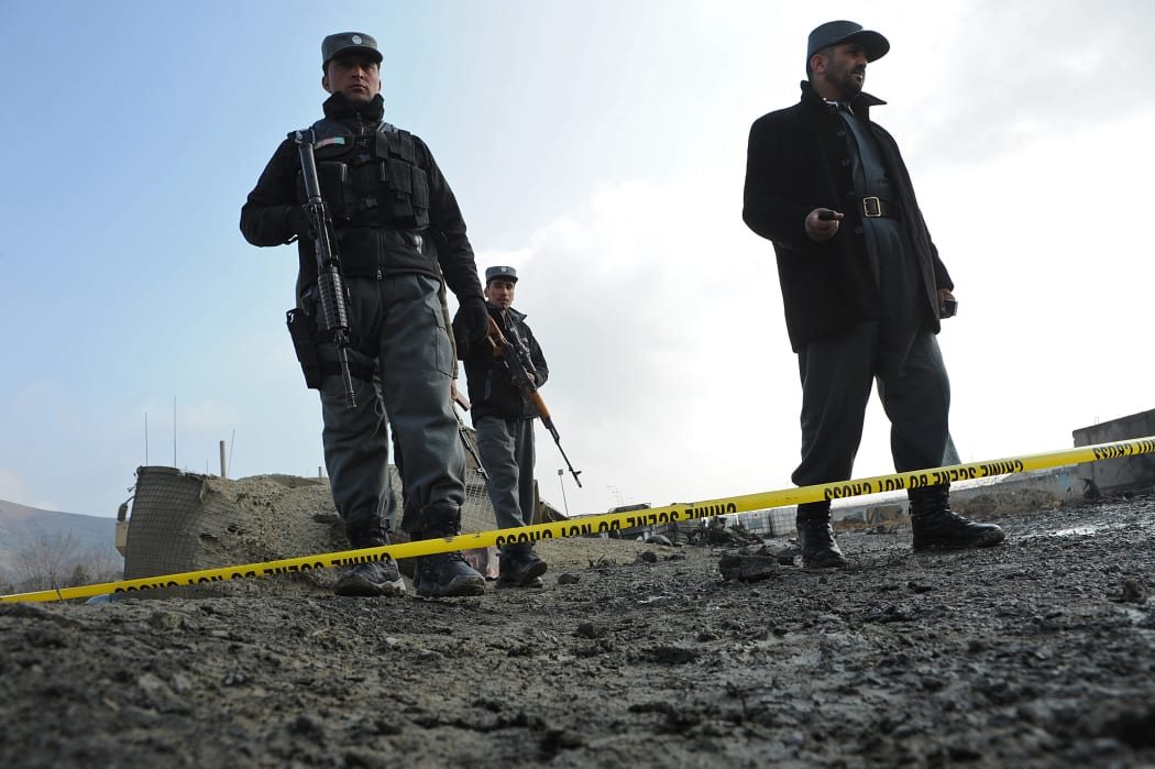 Afghan police stand guard at the site of a suicide attack near a NATO military convoy entering Kabul airport on December 11, 2013.