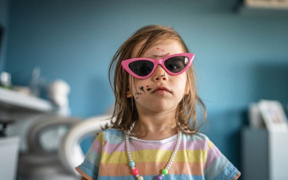caucasian girl toddler with painted color draws and stains on face