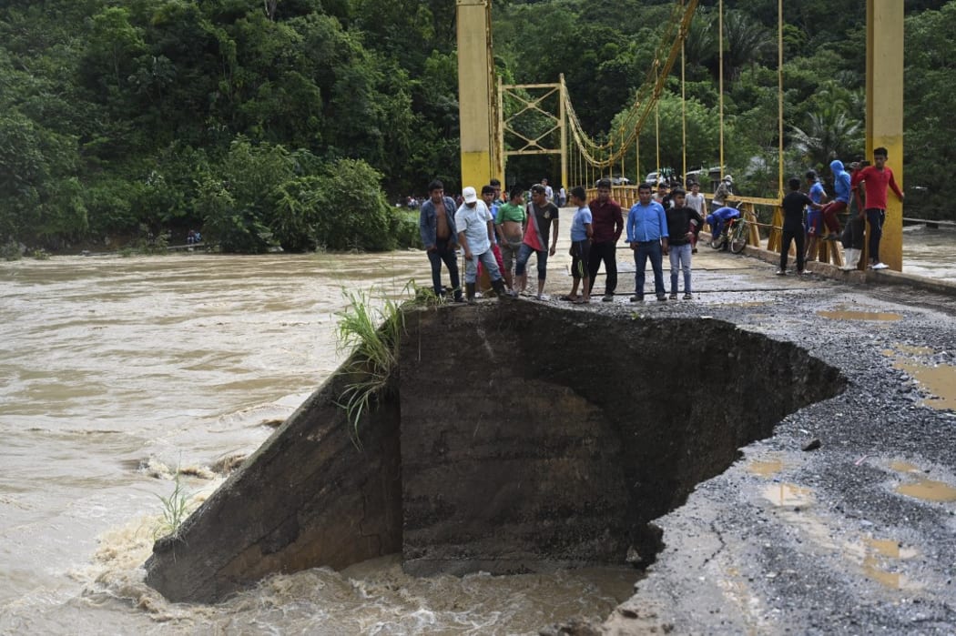 People look at the damage caused by heavy rains brought by Hurricane Eta, now degraded to a tropical storm, on a bridge over the overflooded Cahaboncito river in Panzos, Alta Verapaz, 220 km north of Guatemala City on November 6, 2020.