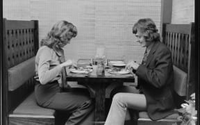 A black and white image showing a couple dining at a First Western Hotel restaurant in New Zealand in the 1970s.