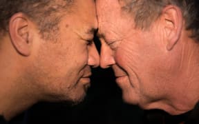 Two older men, one Māori and one Pākehā, hongi.