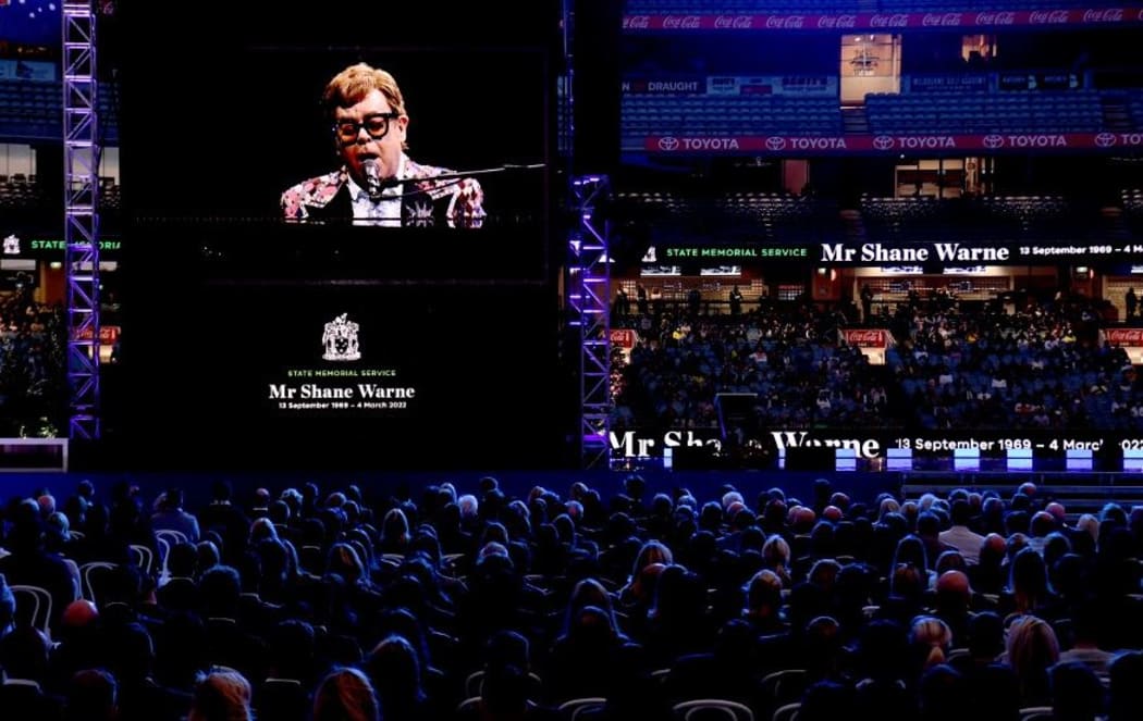 Elton John dedicates a song to Shane Warne on a big screen during the state memorial service for the former Australian cricketer Shane Warne at the Melbourne Cricket Ground (MCG) in Melbourne on March 30, 2022.