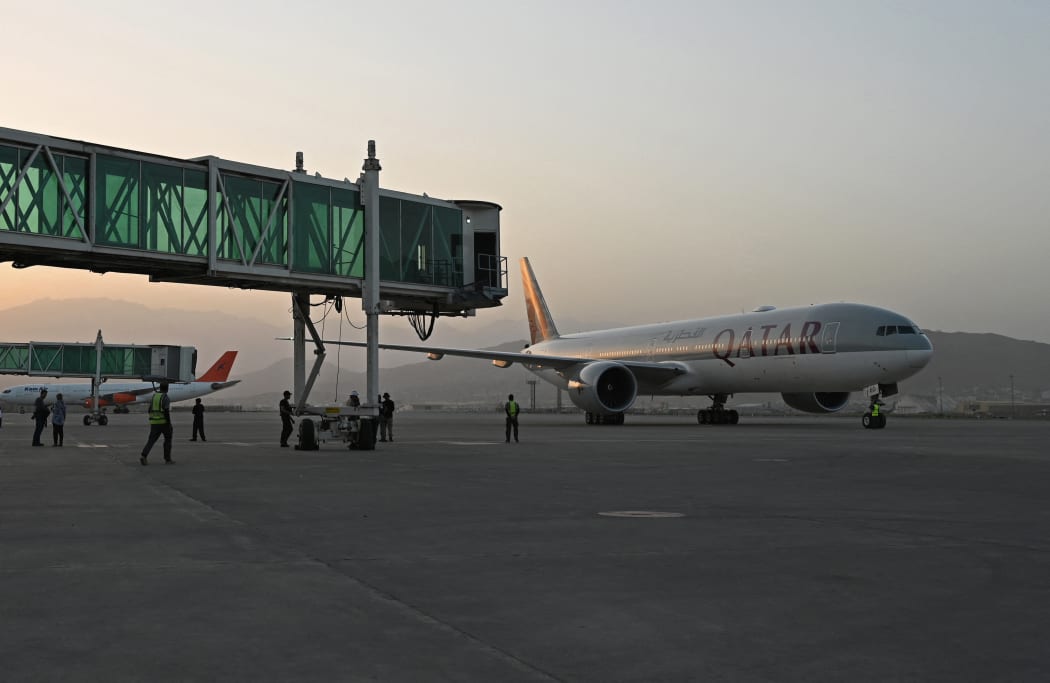 Members of ground staff stand on the tarmac as a Qatar Airways aircraft taxis before taking off from the airport in Kabul on 9 September 2021.