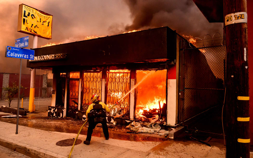 A firefighter douses flames as a liquor store burns during the Eaton fire in the Altadena area of Los Angeles County, California on January 8, 2025. - At least five people are now known to have died in wildfires raging around Los Angeles, with more deaths feared, law enforcement said January 8, as terrifying blazes leveled whole streets, torching cars and houses in minutes.
More than 1,000 buildings have burned in multiple wildfires that have erupted around America's second biggest city, forcing tens of thousands of people from their homes. (Photo by JOSH EDELSON / AFP)
