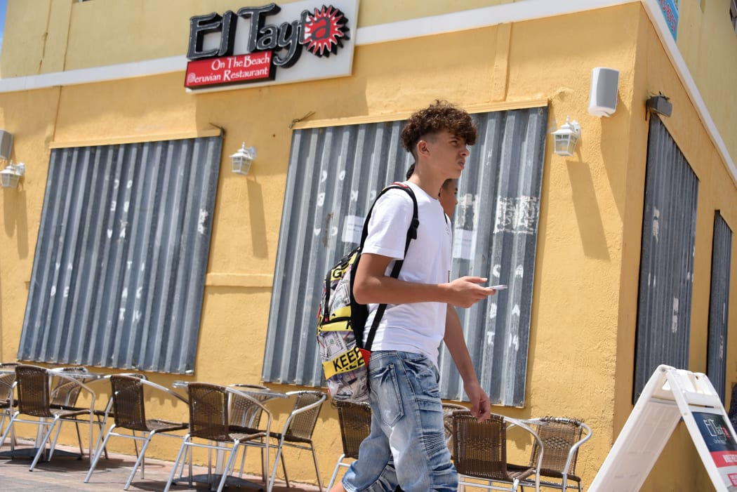 People pass a boarded up business in Hollywood Beach, Florida, as communities prepare for Hurricane Dorian.