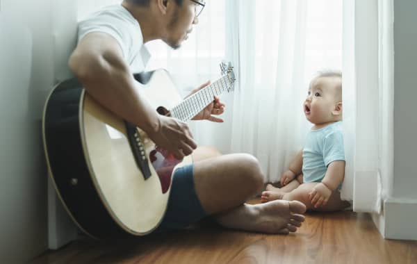 Father playing acoustic guitar to baby