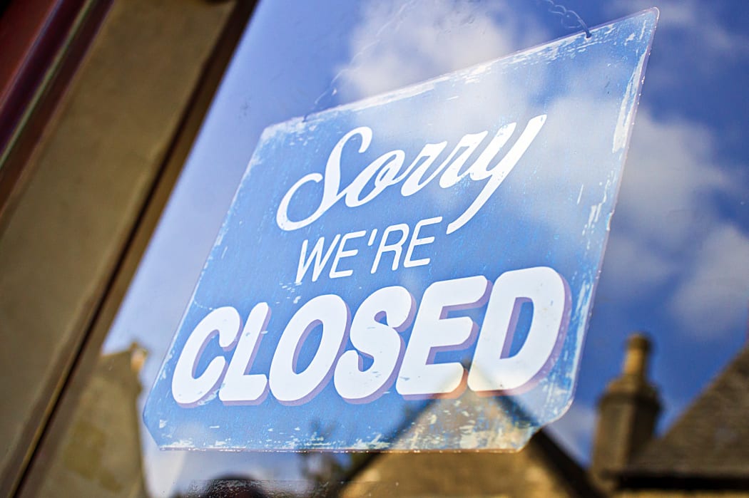 A closed sign hanging in the glass doorway of a shop in the UK