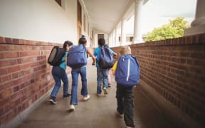 A photo of school kids with one trailing slightly behind