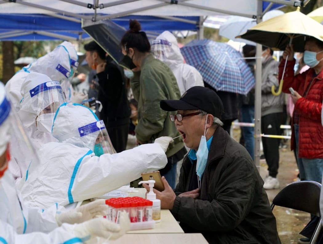 Citizens receive nucleic acid tests at a residential area in east China's Shanghai, March 17, 2022.