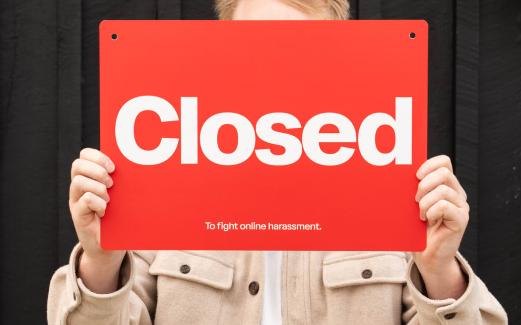 Man holding sign saying 'closed to harassment'