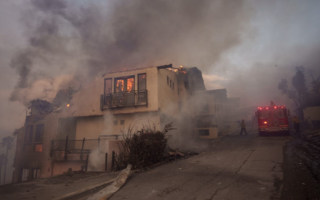 MALIBU, CALIFORNIA - JANUARY 8: Firefighters battle flames from the Palisades Fire on January 8, 2025 in Malibu, California. Fueled by intense Santa Ana Winds, the Palisades Fire has grown to over 2,900 acres and 30,000 people have been ordered to evacuate while a second major fire continues to burn near Eaton Canyon in Altadena.   Eric Thayer/Getty Images/AFP (Photo by Eric Thayer / GETTY IMAGES NORTH AMERICA / Getty Images via AFP)