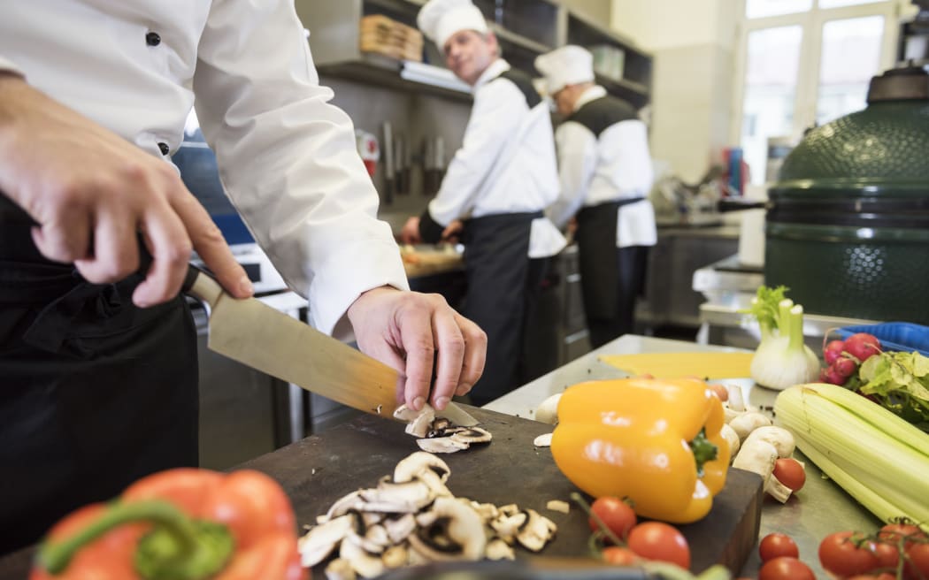 A group of people cooking in a commercial kitchen.