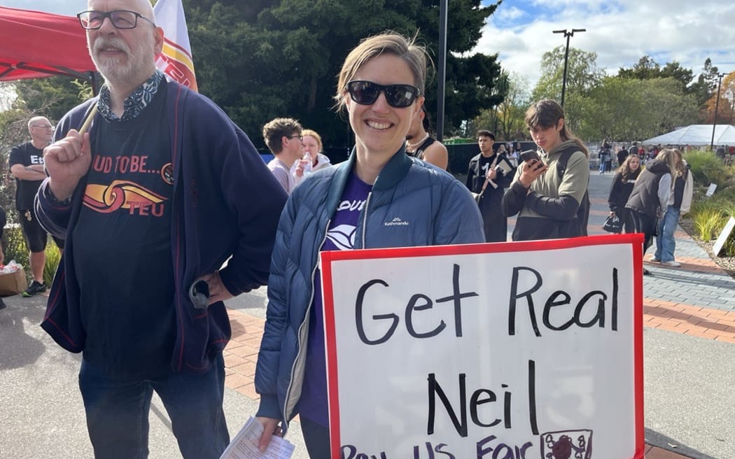 A protester holds a placard with a message for vice-chancellor Professor Neil Quigley "Get Real Neil, Pay Us Fair", at a demonstration by union staff members at the University of Waikato on 24 May, 2024.