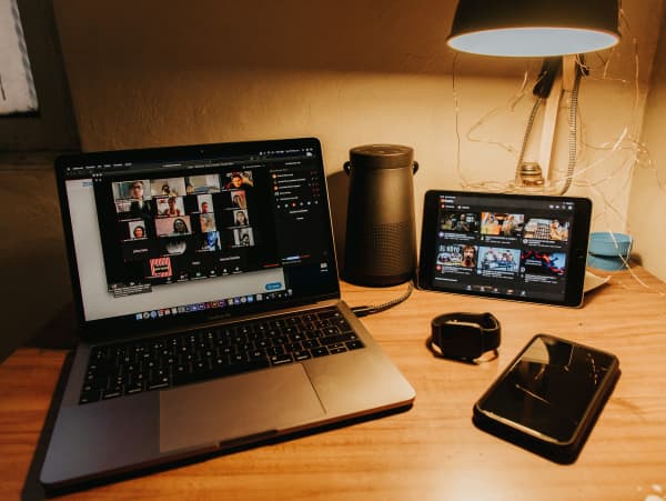 A laptop, tablet and mobile phone on a wooden table illustrating video calling.