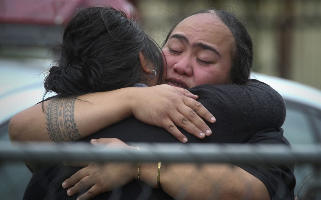 Treicee Taufa, right, is comforted at the scene of a house fire which claimed the life of her daughter, Adele Taufa, and 10 others.