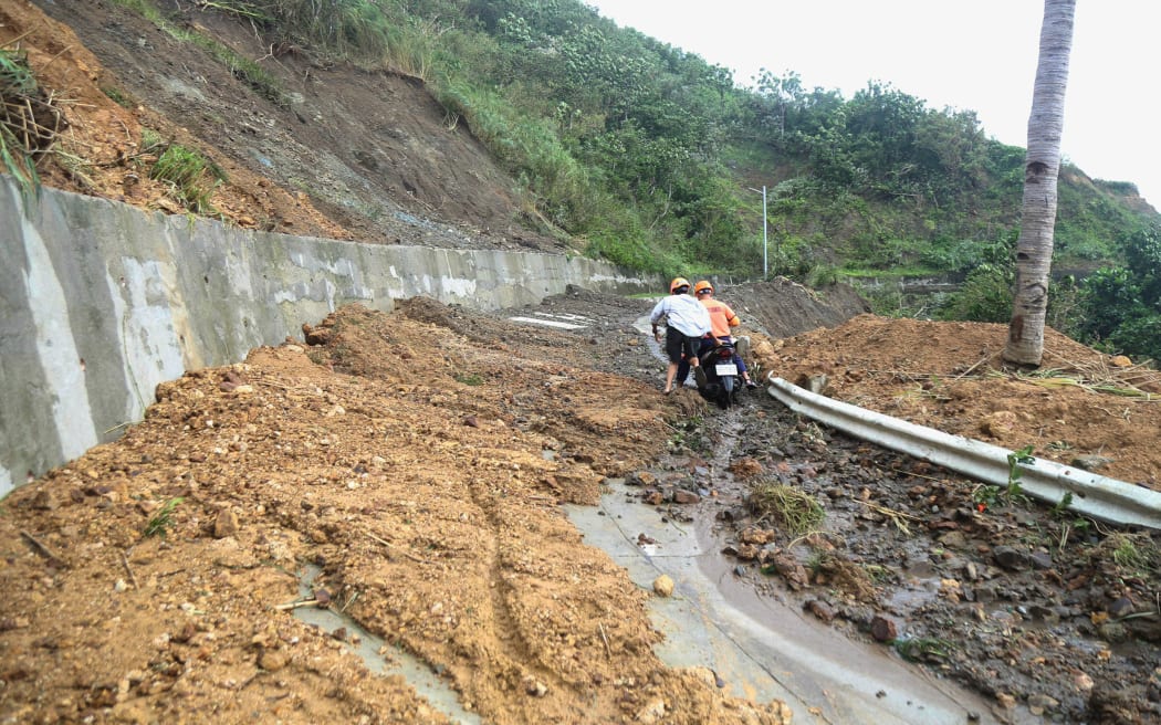 Two men negotiate a landslide after Typhoon Ragasa in Uyugan, Batanes province, northern Philippines on September 23.