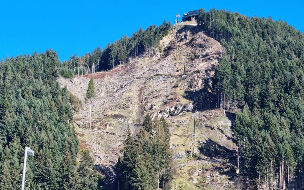 A view of the Skyline gondola in Queenstown. There are logs and slash lying on the hillside on the left, above the cemetery.