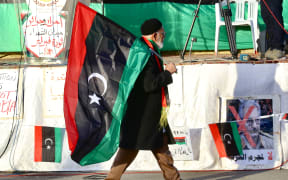 An old man carries a flag of Libya during a protest against the attacks and ceasefire violations in Tripoli on January 24, 2020.