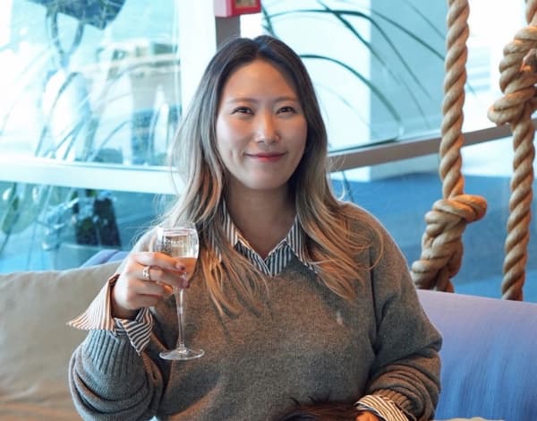 Auckland-based content creator Jasmine Kim smiling while holding a wine glass.