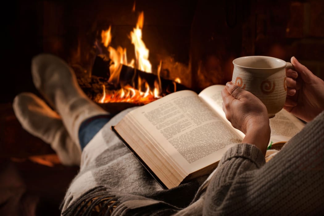 woman with mug and book by the fire