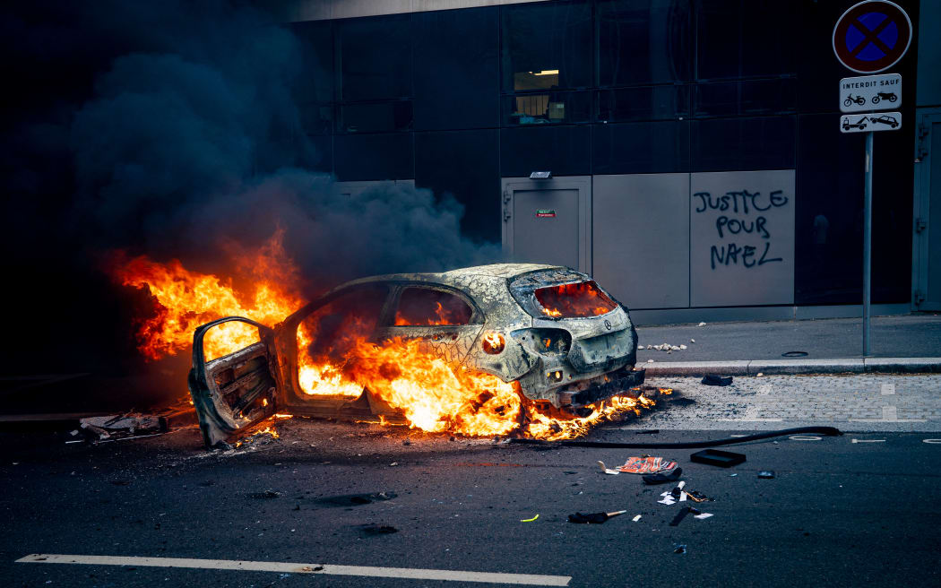 France, Nanterre, 2023-06-29. White march following the death of Nahel, a 17-year-old teenager shot dead by a member of the police force after refusing to obey at the wheel of his car in Nanterre. The participants and their families demand justice for Nahel, the young man killed by a police officer on Tuesday June 27, 2023 during a traffic stop. His death sparked a revolt in working-class neighborhoods and suburbs. Nanterre, Paris suburbs, Thursday June 29, 2023. In the photo: violent clashes between some housing estate youths and the police, scenes of rioting. Mercedes car on fire, billowing flames and black smoke, Justice for Nael tag. Photography by Amaury Cornu / Hans Lucas.
France, Nanterre, 2023-06-29. Marche blanche suite a la mort de Nahel, jeune adosescent de 17 ans abattu par un membre des forces de l ordre apres un refus d obtemperer au volant de sa voiture a Nanterre. Les...