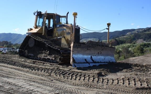 Two streetlight-like poles sticking up either side of the blade of this bulldozer are GNSS units that enable the machine to know exactly where it is digging, with millimetre accuracy.