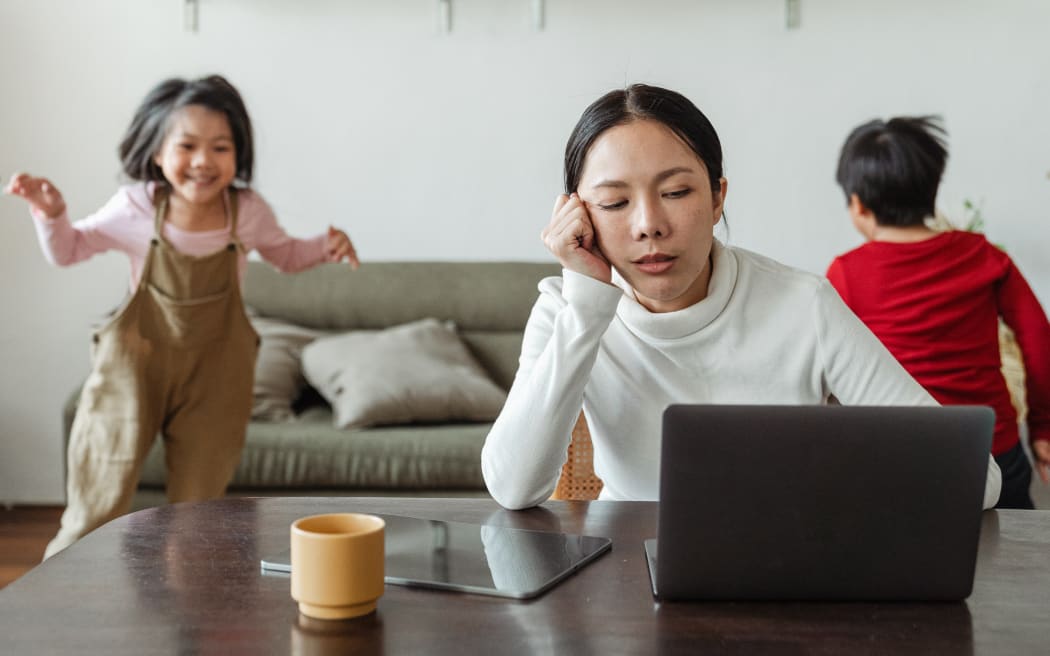 woman with eyes closed and 2 children playing behind her