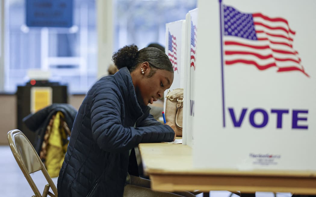 A woman casts her ballot during early voting for the US general election at a polling station at Ottawa Hills High School in Grand Rapids, Michigan, on November 3, 2024. (Photo by KAMIL KRZACZYNSKI / AFP)