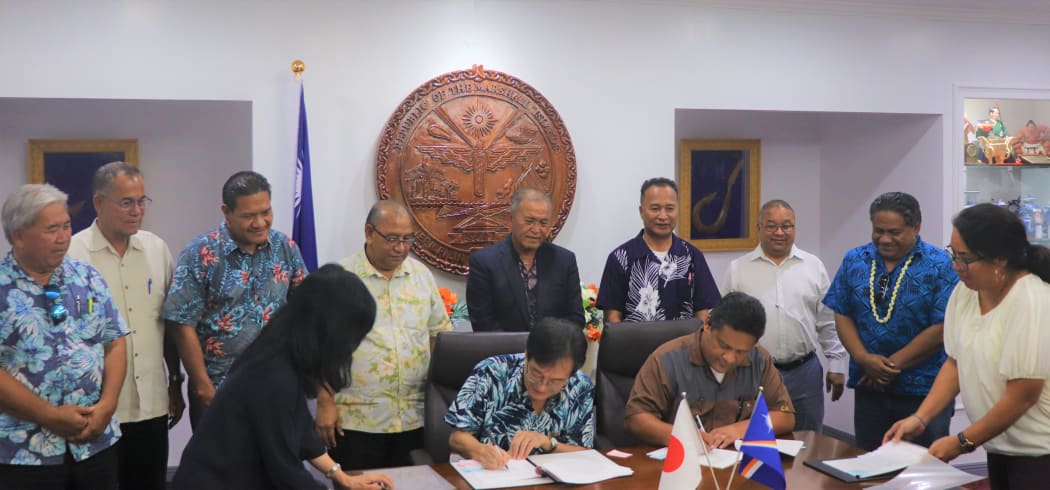 Japan Ambassador Norio Saito and Marshall Islands Foreign Minister Casten Nemra sign two agreements as President David Kabua and his Cabinet look on