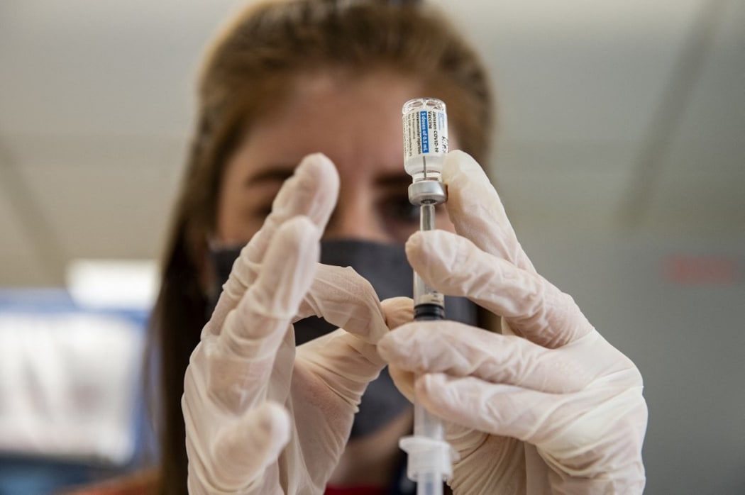 (FILES) In this file photo taken on March 4, 2021 Home base primary care Pharmacist Erin Emonds logs onto a computer before filling syringes the Johnson & Johnson Janssen vaccine  in Boston, Massachusetts.