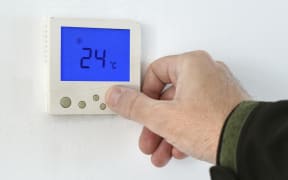 Man using a home heating and cooling control unit. (Photo by IGOR STEVANOVIC/SCIENCE PHOTO LI / IST / Science Photo Library via AFP)