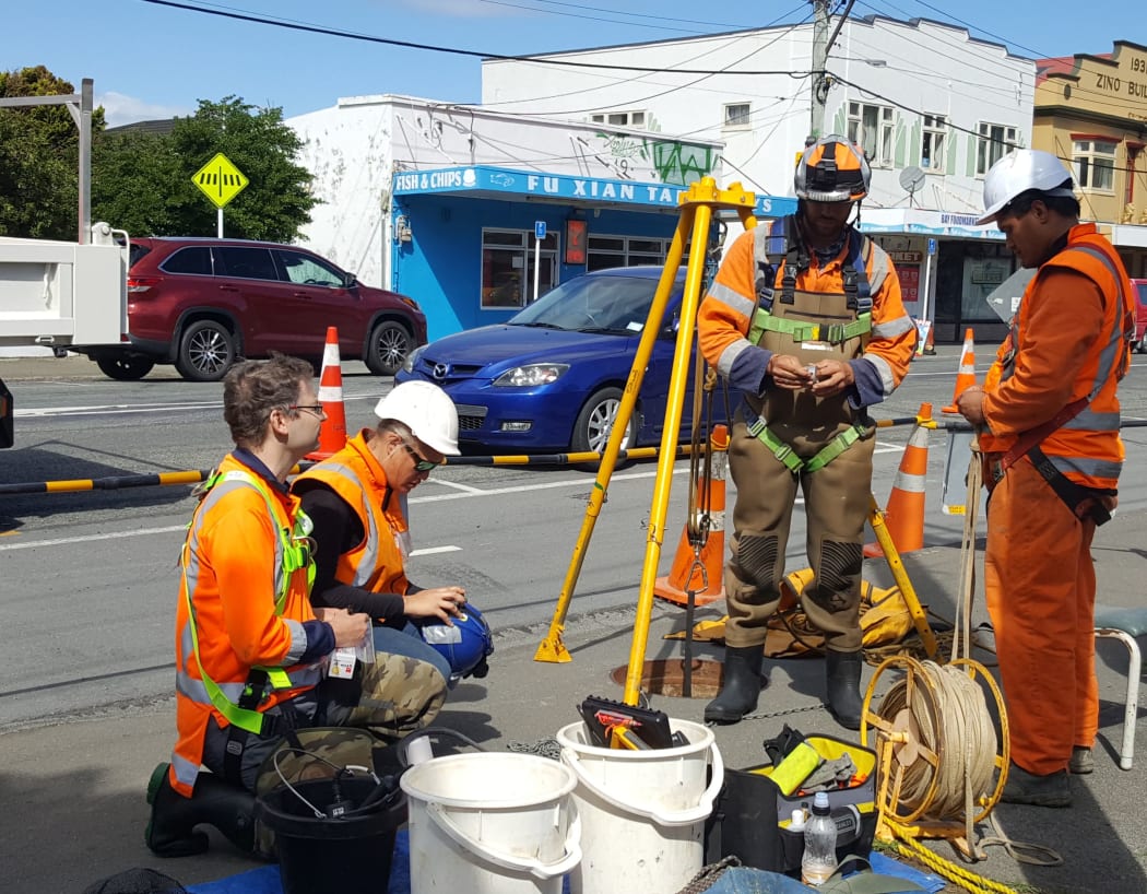 Freshwater ecologist Alex James (left)
 and Silver Lining Contracting staff discuss access to the underground culvert through the open maintenance hole.