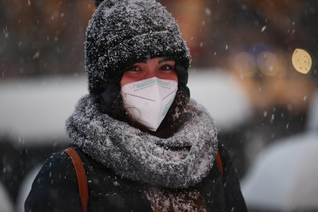 A woman stands at Times Square as snow falls across the city.