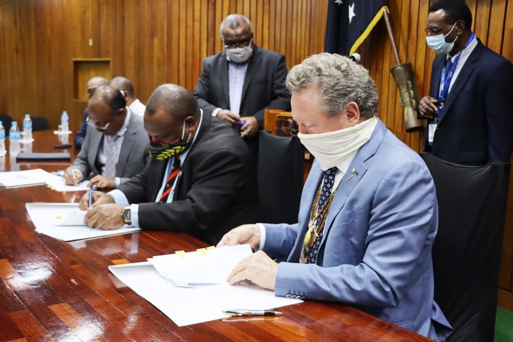 Seated: Papua New Guinea's State Enterprises Minister, Sasindran Muthuvel (left), Prime Minister James Marape (centre) and the chairman of Fortescue Metals Group of Australia, Andrew Forrest, sign an agreement, Port Moresby, 1st September 2020.