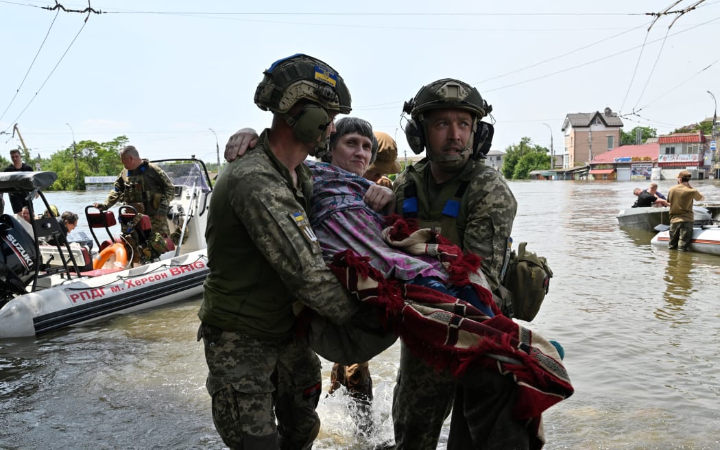 Ukrainian servicemen carry a disabled resident from a boat during an evacuation from a flooded area in Kherson on June 8, 2023, after the destruction of the Kakhovka dam.