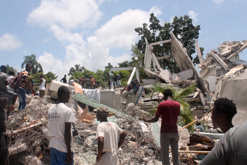 People search through the rubble of what used to be the Manguier Hotel after the earthquake hit on 14 August 
 2021 in Les Cayes, southwest Haiti.