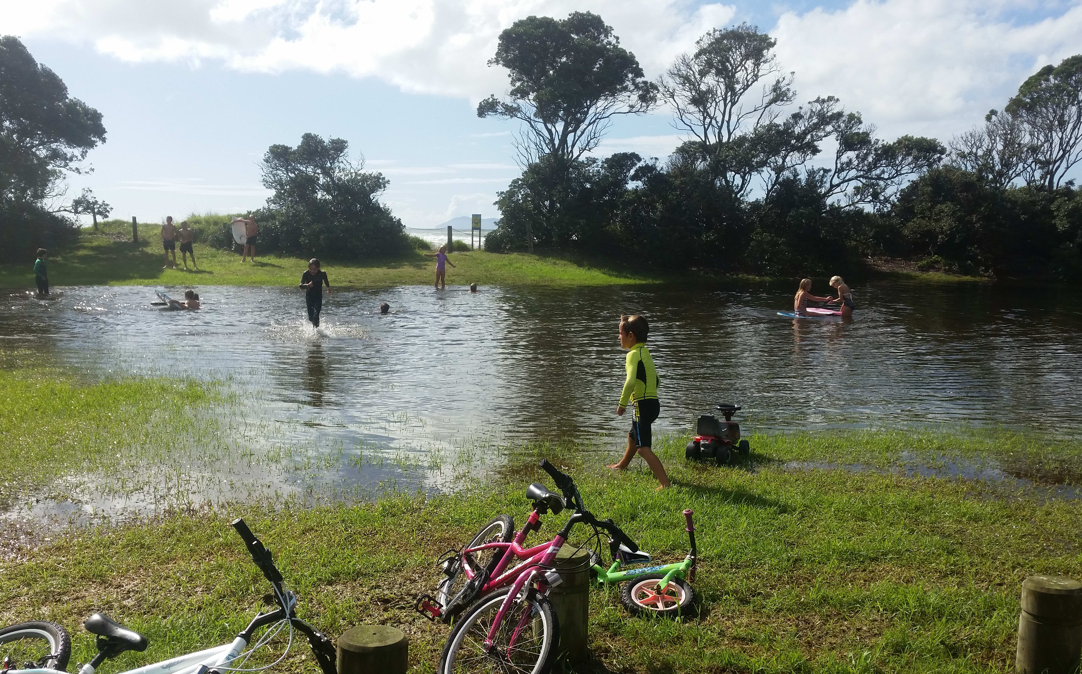 Children play in a newly-formed pool at a Waihi Beach park.