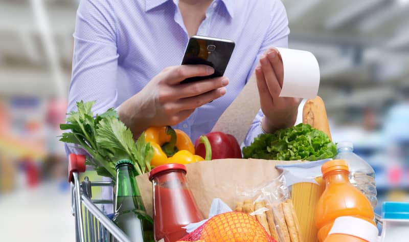 Woman checking the grocery receipt using her smartphone