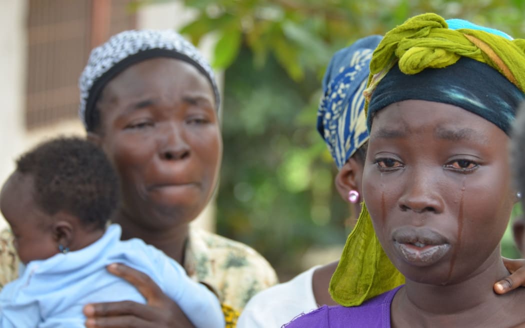 A woman cries after the death of her husband from Ebola.