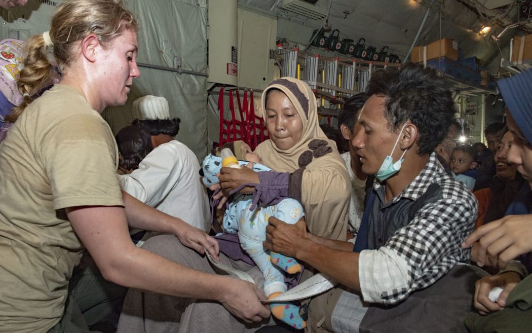 CPL Toni Thompson loads families as they board a NZ Defence Force Hercules in Palu. The evacuees were taken to Balikpapan airport.